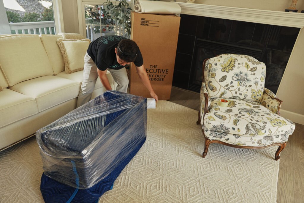Mover handling shrink-wrapped furniture with care inside a home