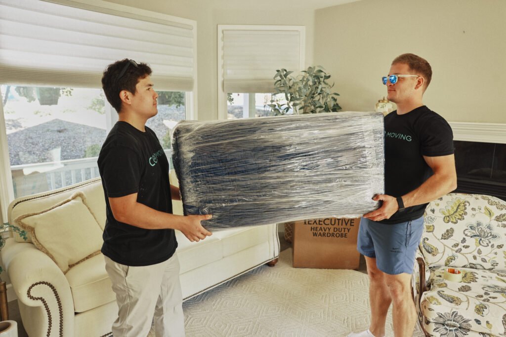 Movers carrying shrink-wrapped furniture to protect it inside the moving truck
