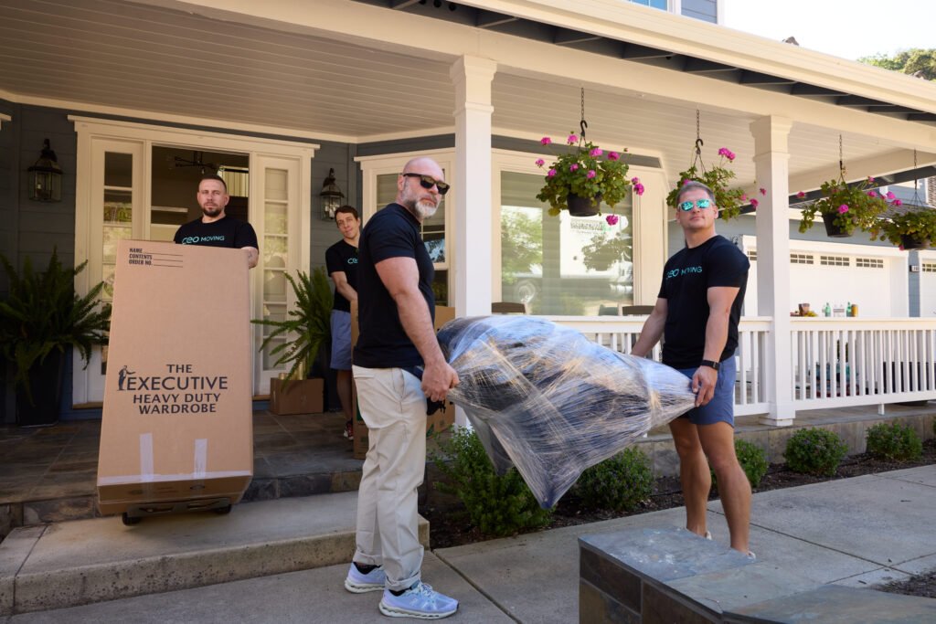 CEO Moving crew carrying wrapped furniture out the front door on a last minute moving day