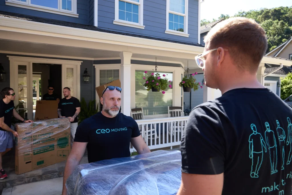 CEO Moving crew carrying wrapped furniture out of a home on moving day — timing the best month to move