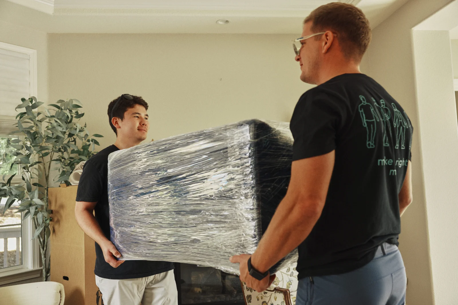 Two movers carrying wrapped office furniture during a commercial relocation in the Bay Area