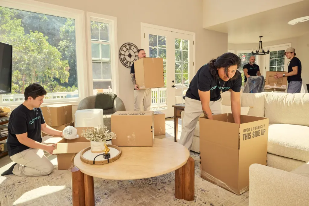 Movers packing and inventorying household items in a Bay Area home before a written moving estimate